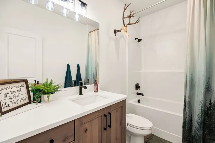 White vanity with wood-finish cabinetry, integrated sink, and dark-finish hardware