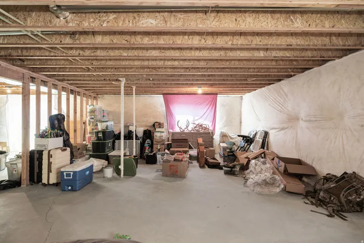 Unfinished basement with concrete flooring, exposed wood ceiling joists, and framed partition walls