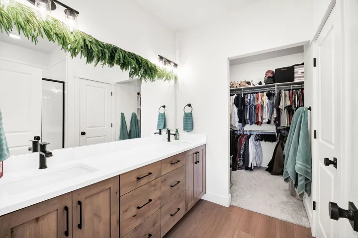 Double vanity with integrated sinks, white countertop, wood-finish cabinetry, and black fixtures