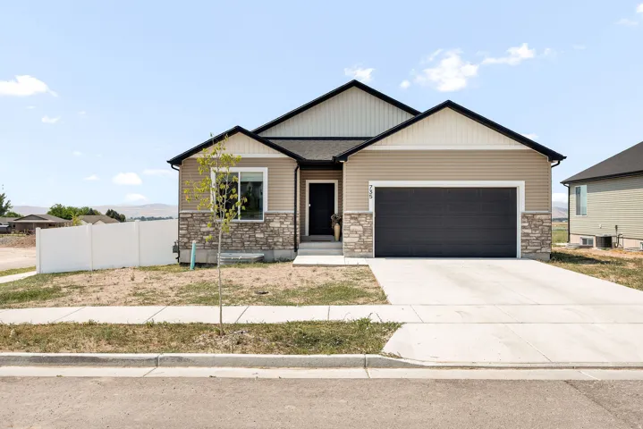 Contemporary exterior featuring stone accents, horizontal siding, a dark garage door, and a concrete driveway