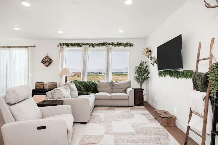 Recessed lighting, wood-finish flooring, multiple large windows, and a mounted television