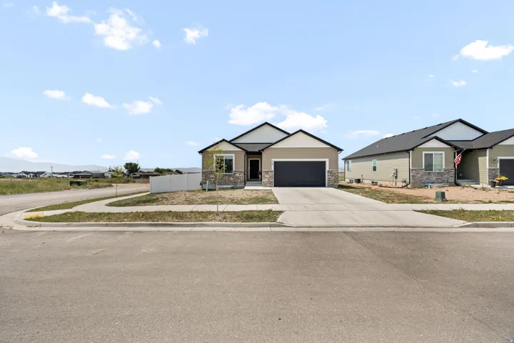 Single-story residence featuring a two-car garage, stone and siding exterior, and a concrete driveway