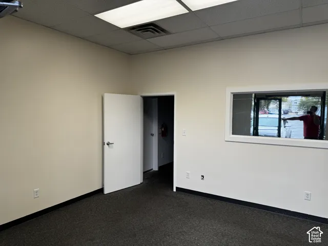 Interior room featuring neutral wall paint, charcoal carpeting, a glass-paneled interior window, and a recessed ceiling lighting fixture