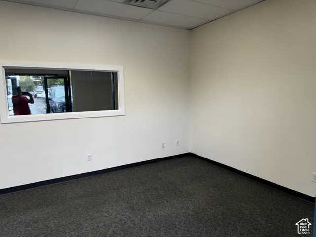 Interior space featuring neutral wall paint, carpeted flooring, and a rectangular window with a white frame