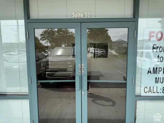 Double glass entry doors with a light blue frame, featuring transom window with horizontal blinds