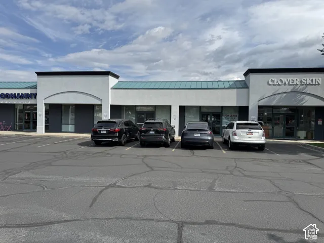 Commercial storefront building with a light-colored stucco facade and dark-colored trim
