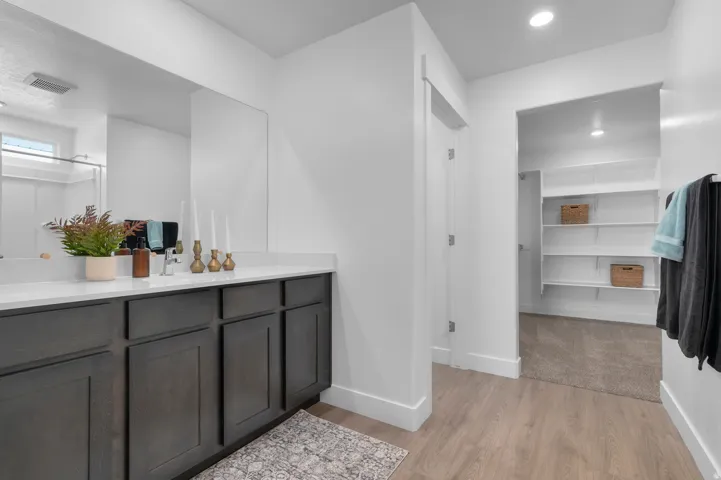 Built-in vanity with dark wood-finish cabinetry, light-toned countertop, and integrated sink