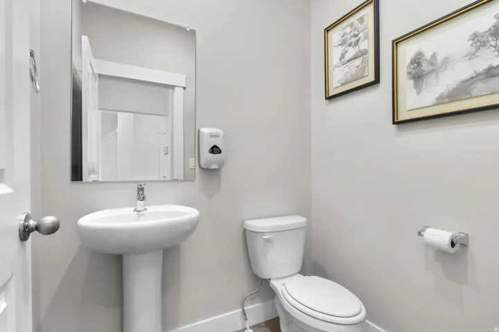 Pedestal sink, wall-mounted mirror, and white toilet