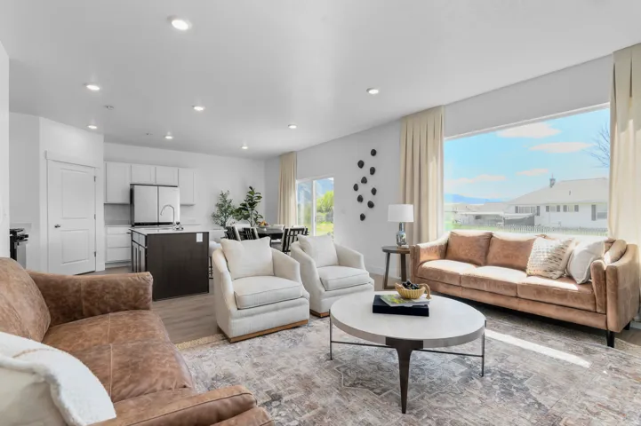 Open-concept living area with recessed lighting, wood-finish flooring, a kitchen island, and a large picture window