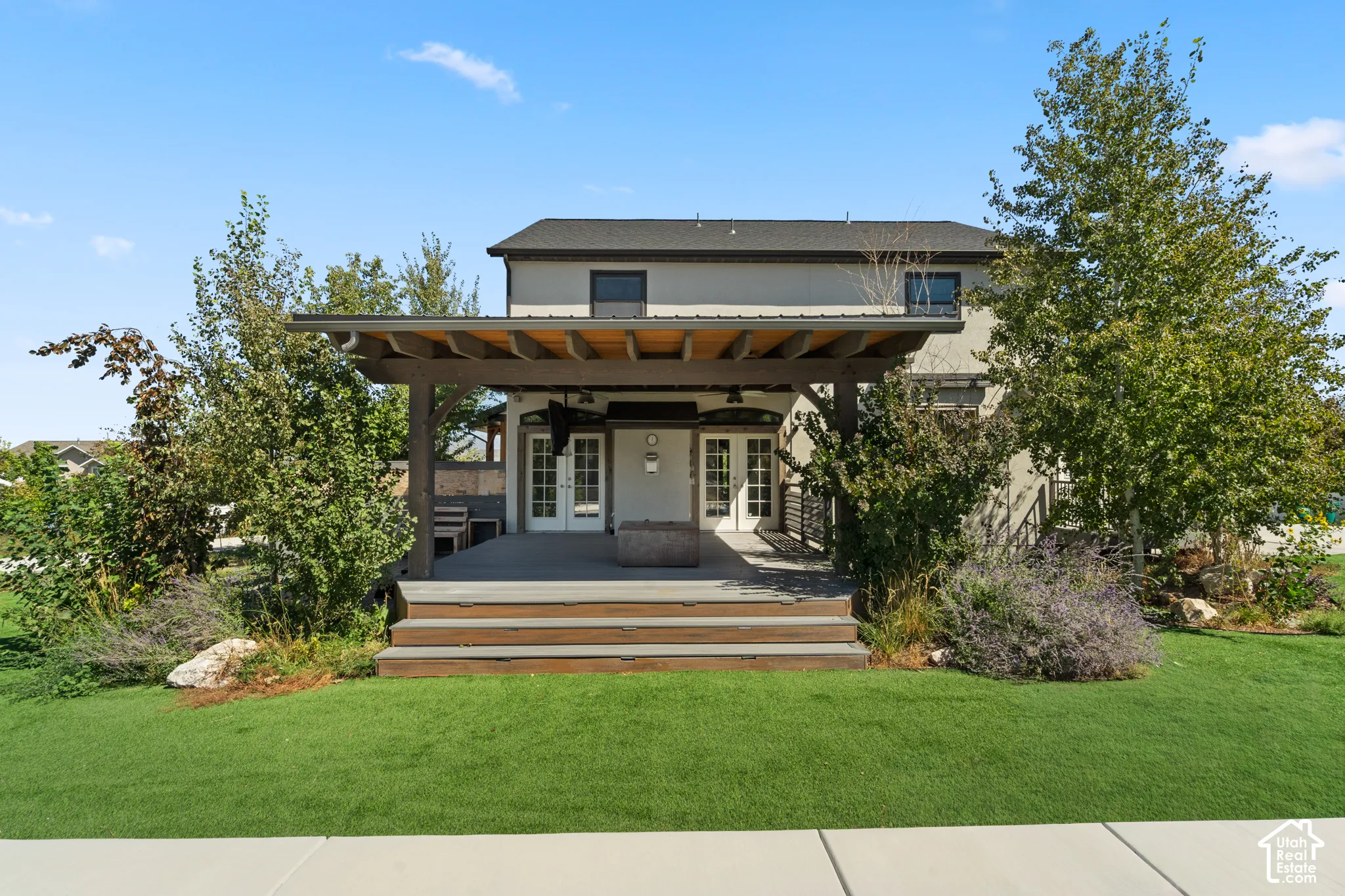 Expansive rear patio featuring a wood pergola, tiered composite decking, and integrated fire pit
