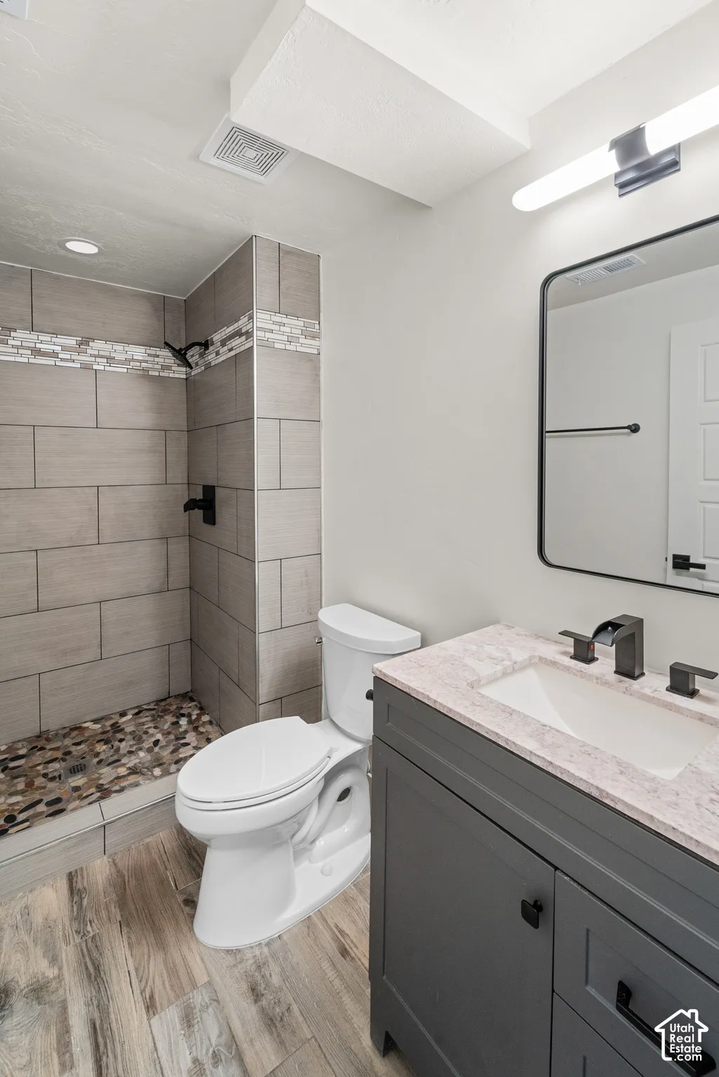 Walk-in shower with natural stone floor, subway tile walls, and mosaic accent
