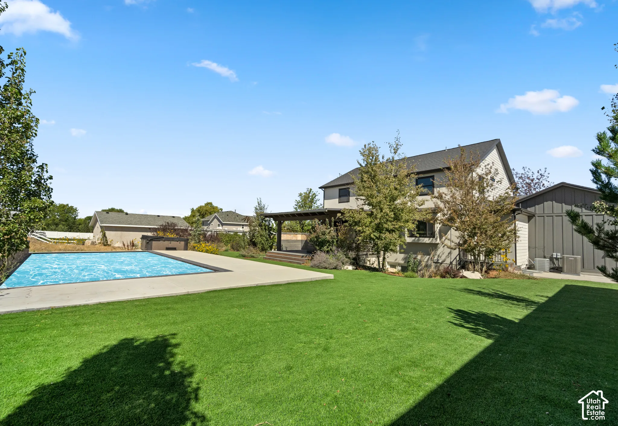 Expansive yard with a rectangular swimming pool, concrete pool deck, and a wooden pergola structure