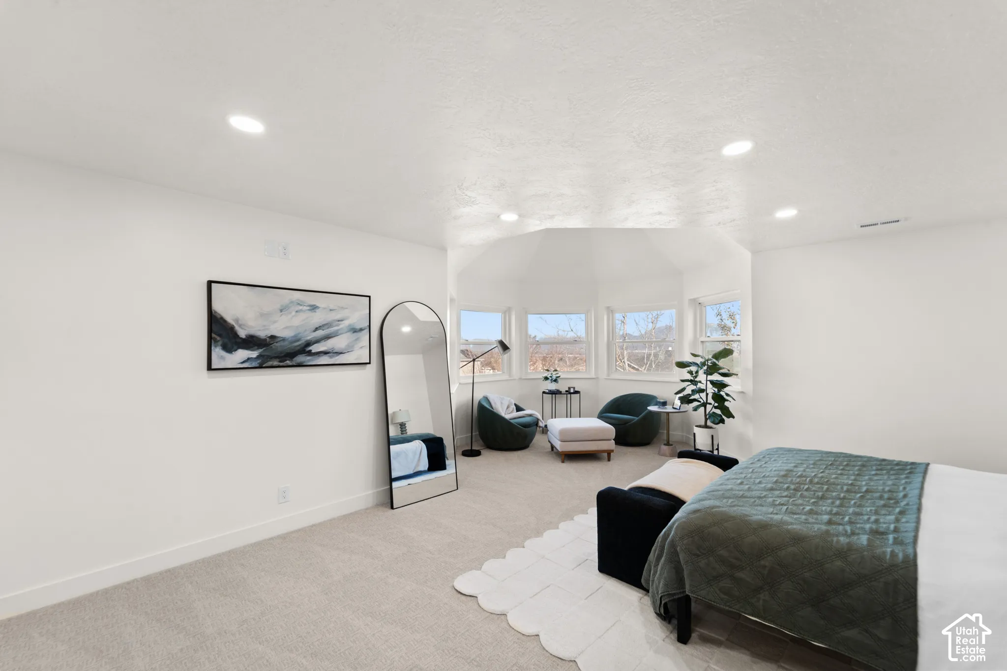 Recessed ceiling lighting, light-toned carpeting, white wall finishes, multiple windows, and a multi-faceted ceiling design
