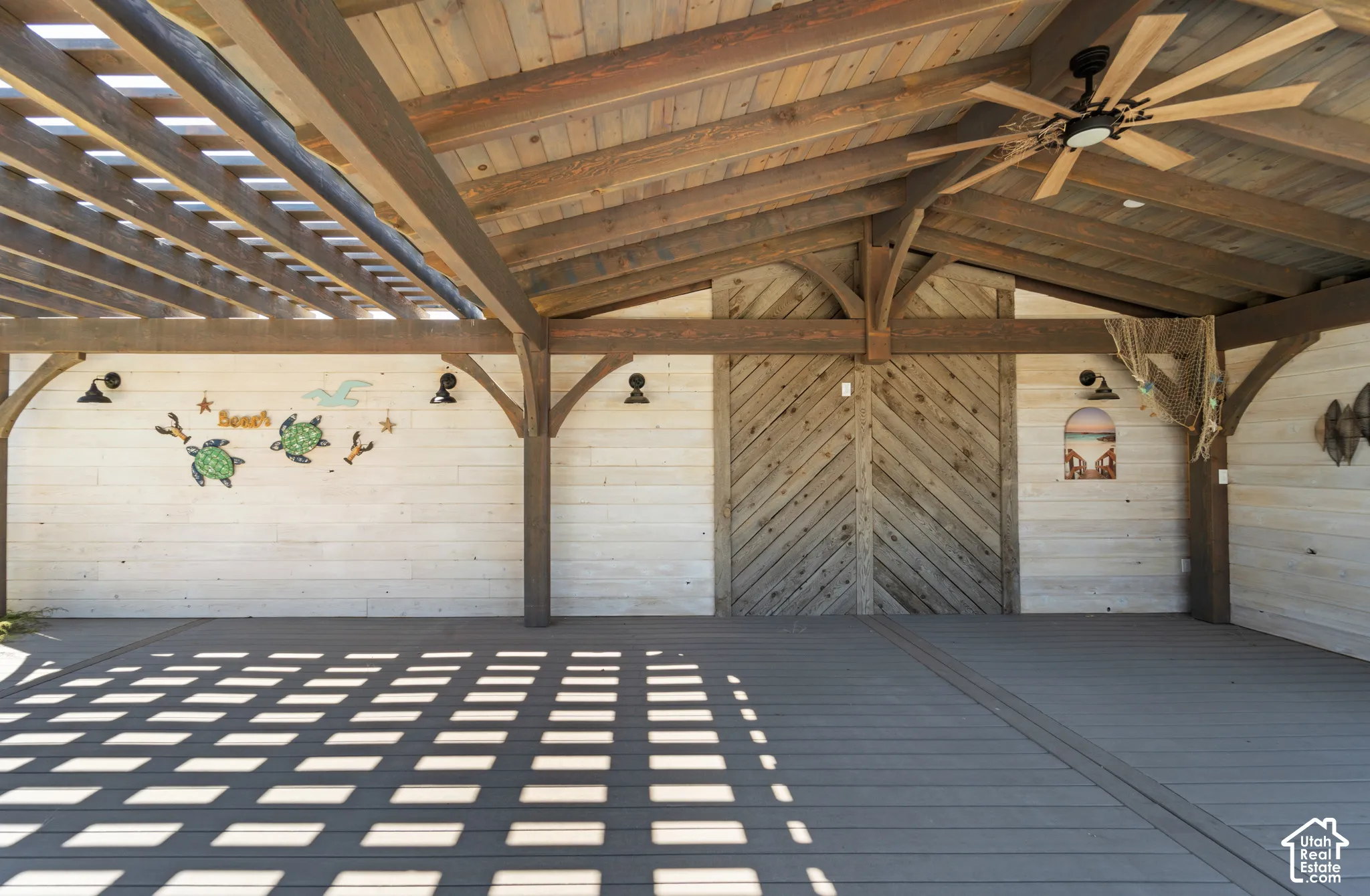 Expansive outdoor structure featuring a slatted pergola roof, a solid wood-beamed ceiling, and durable composite decking