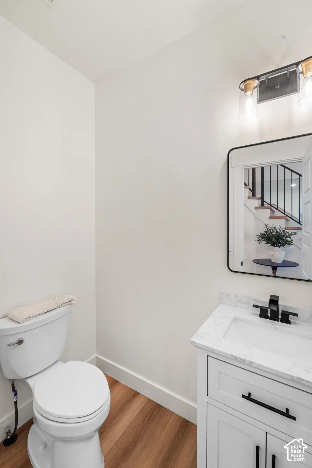 White vanity with a rectangular undermount sink, dark-toned faucet, and light-toned countertop