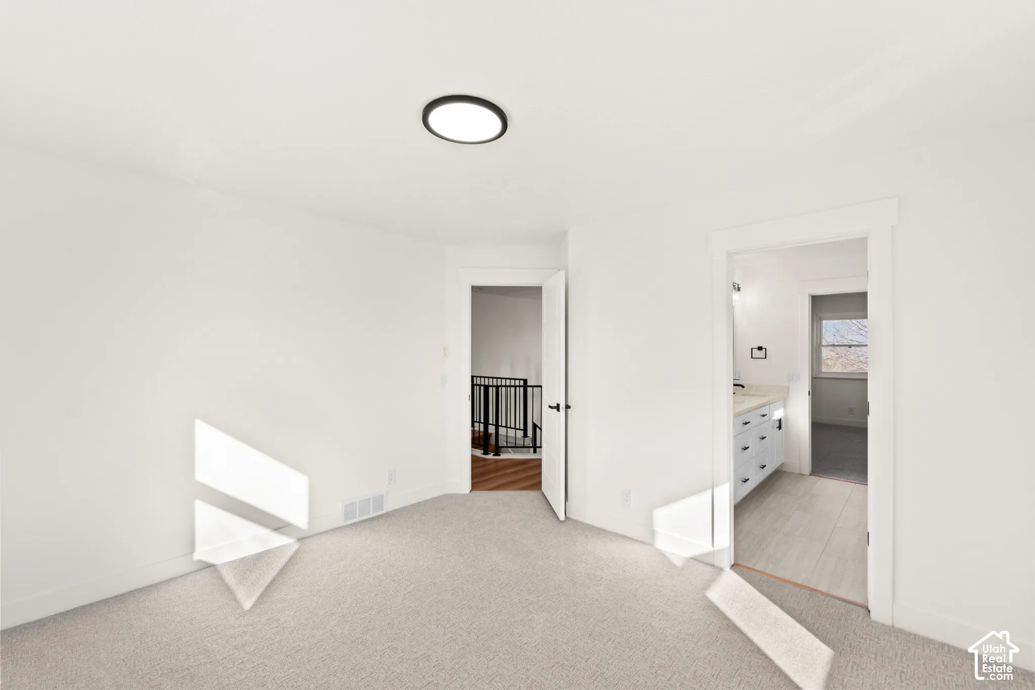 Plush carpet flooring, neutral wall tones, and a contemporary flush-mount ceiling light