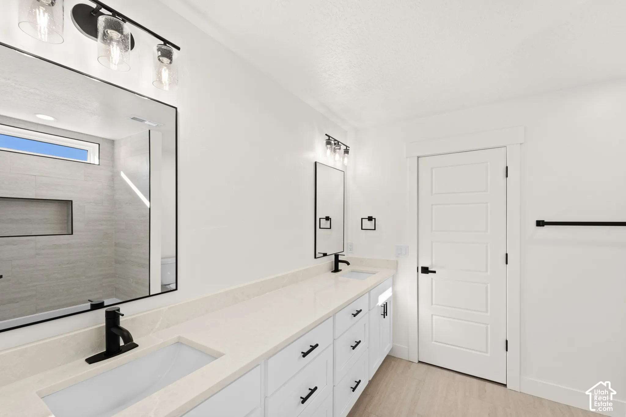 Dual sink vanity with stone-finish countertop, black fixtures, and integrated rectangular sinks