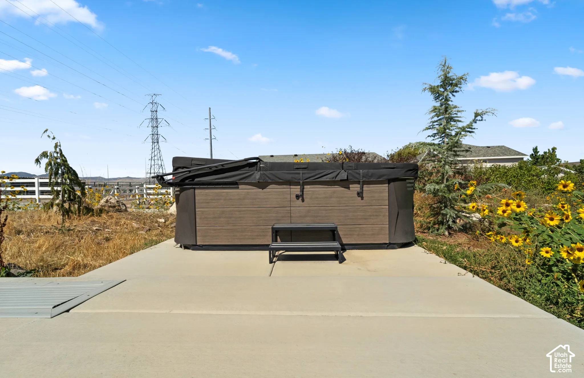 Hot tub with brown wood-finish siding, accompanying steps, and a durable cover