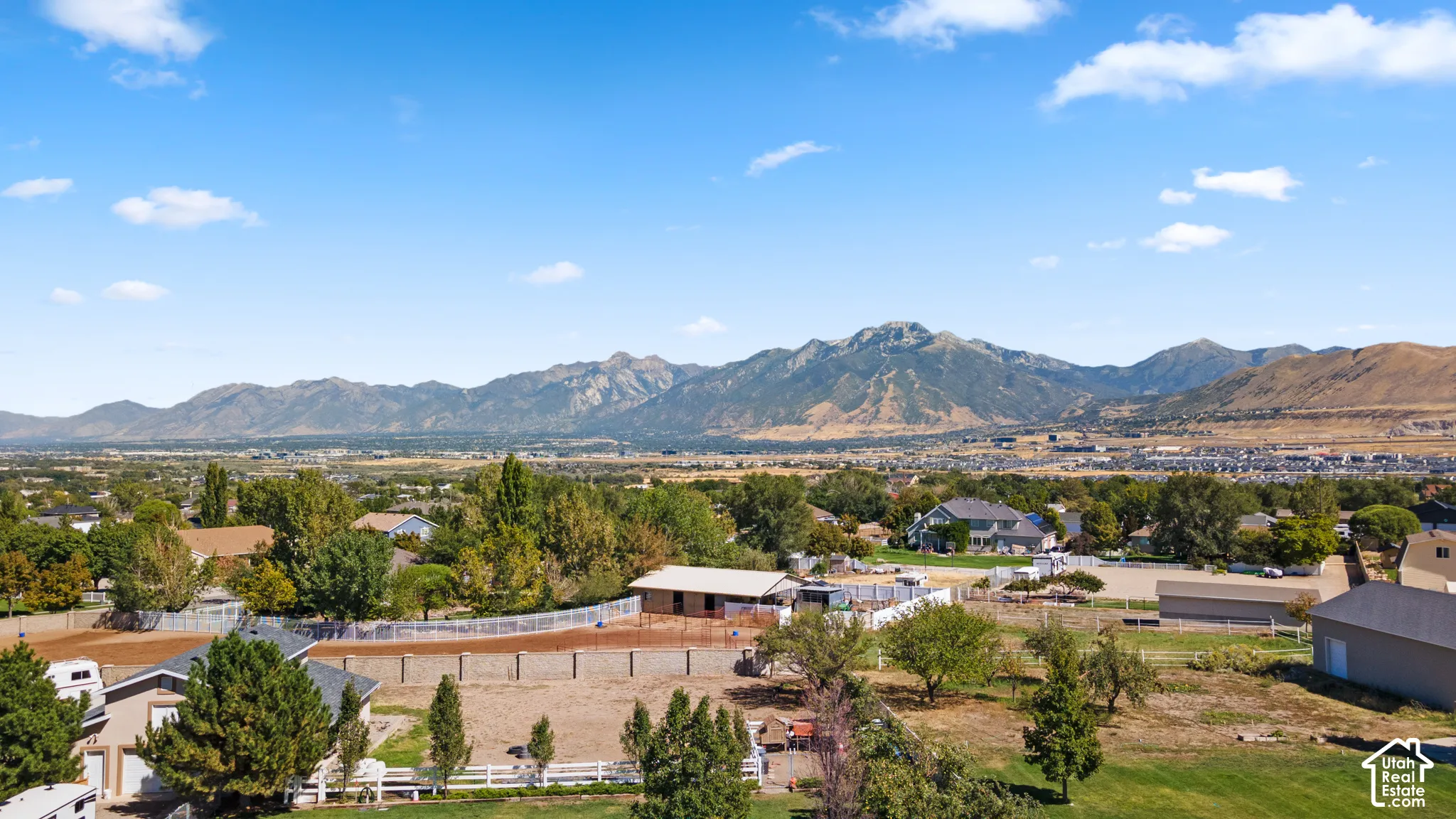 Expansive property featuring a flat, open lot, a white perimeter fence, and a distant mountain range backdrop