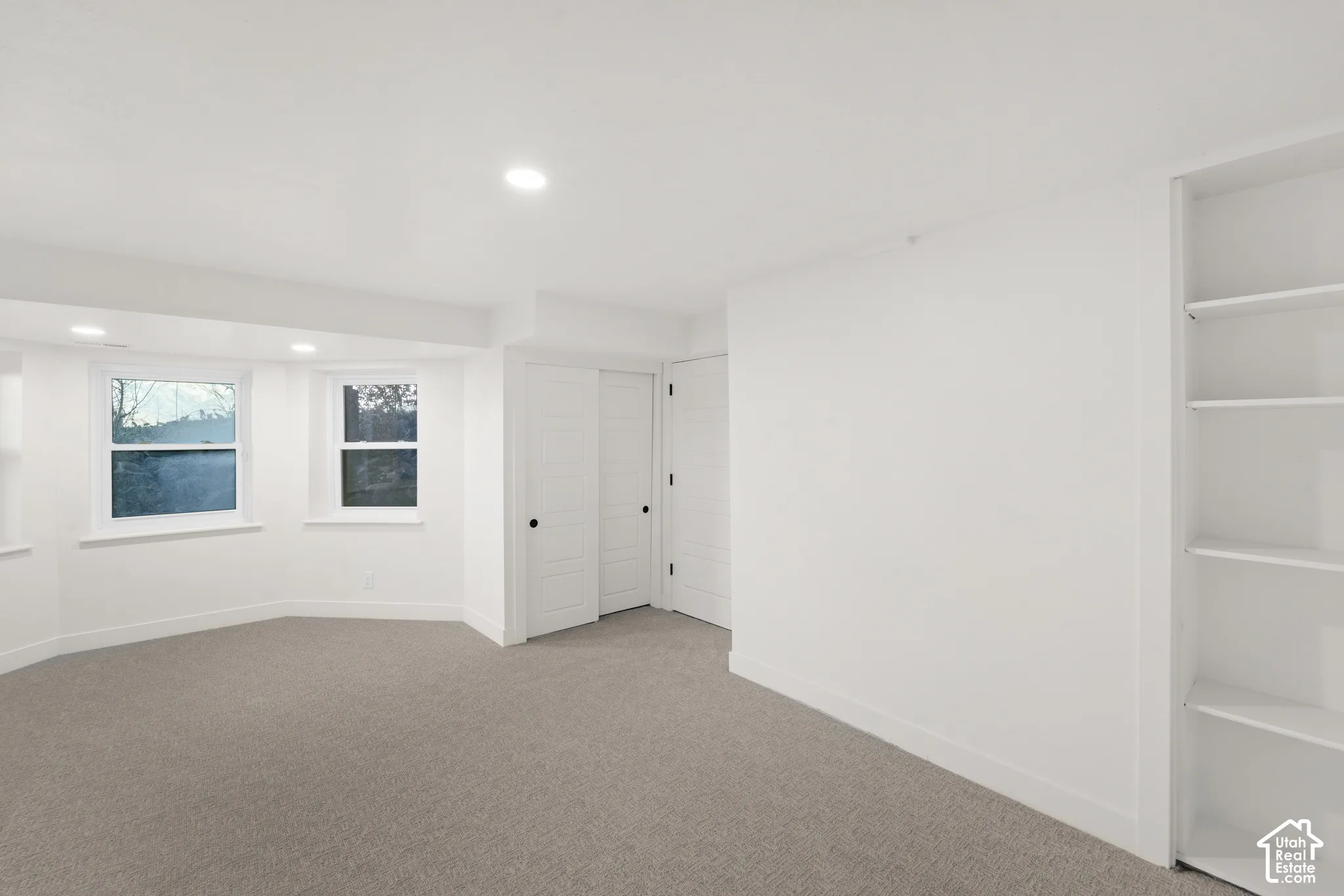 Recessed lighting, light gray carpeting, built-in shelving, white trim, and white paneled doors with black hardware