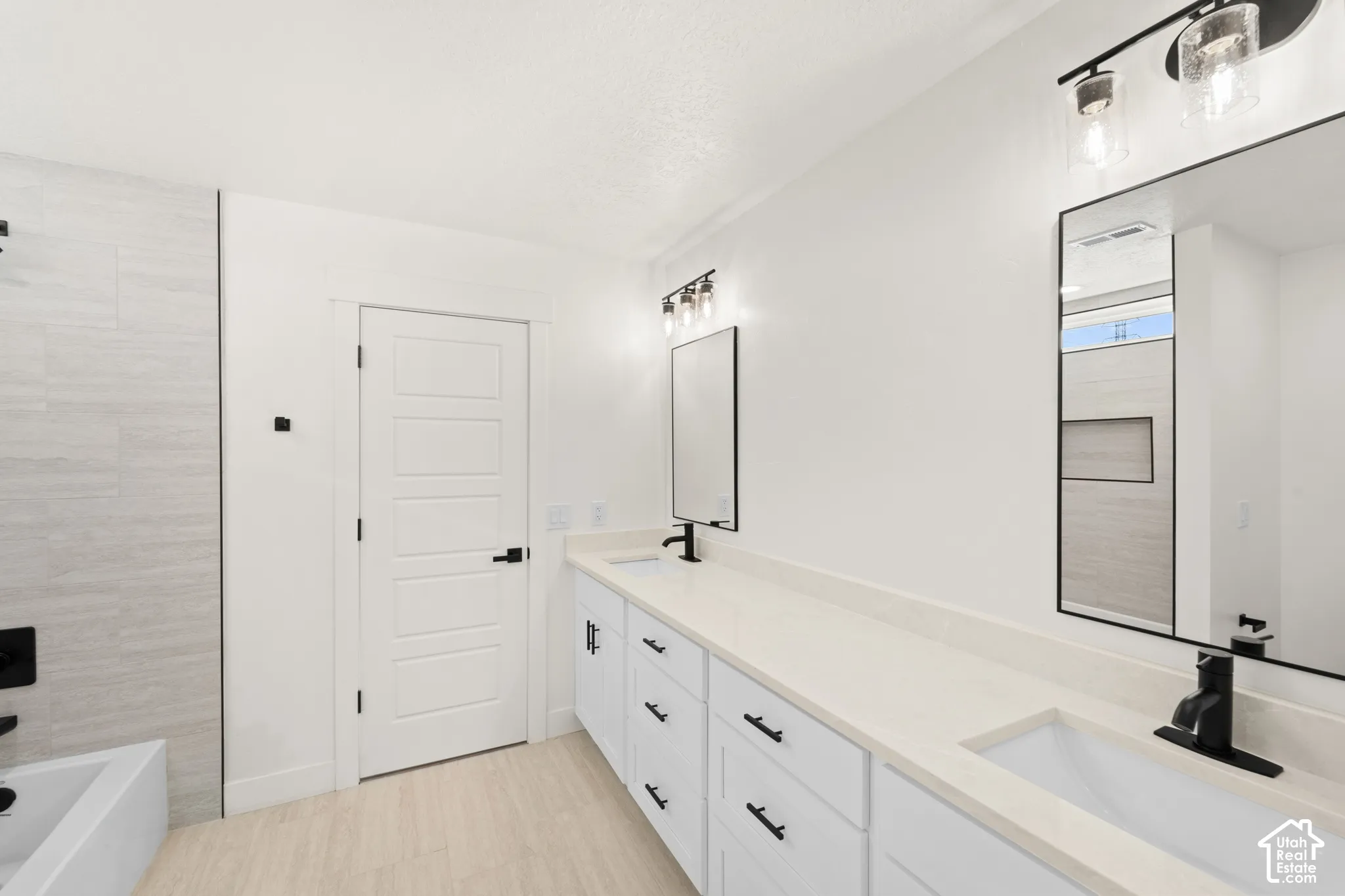 Dual vanity with matte black fixtures, light-toned countertops, and framed mirrors