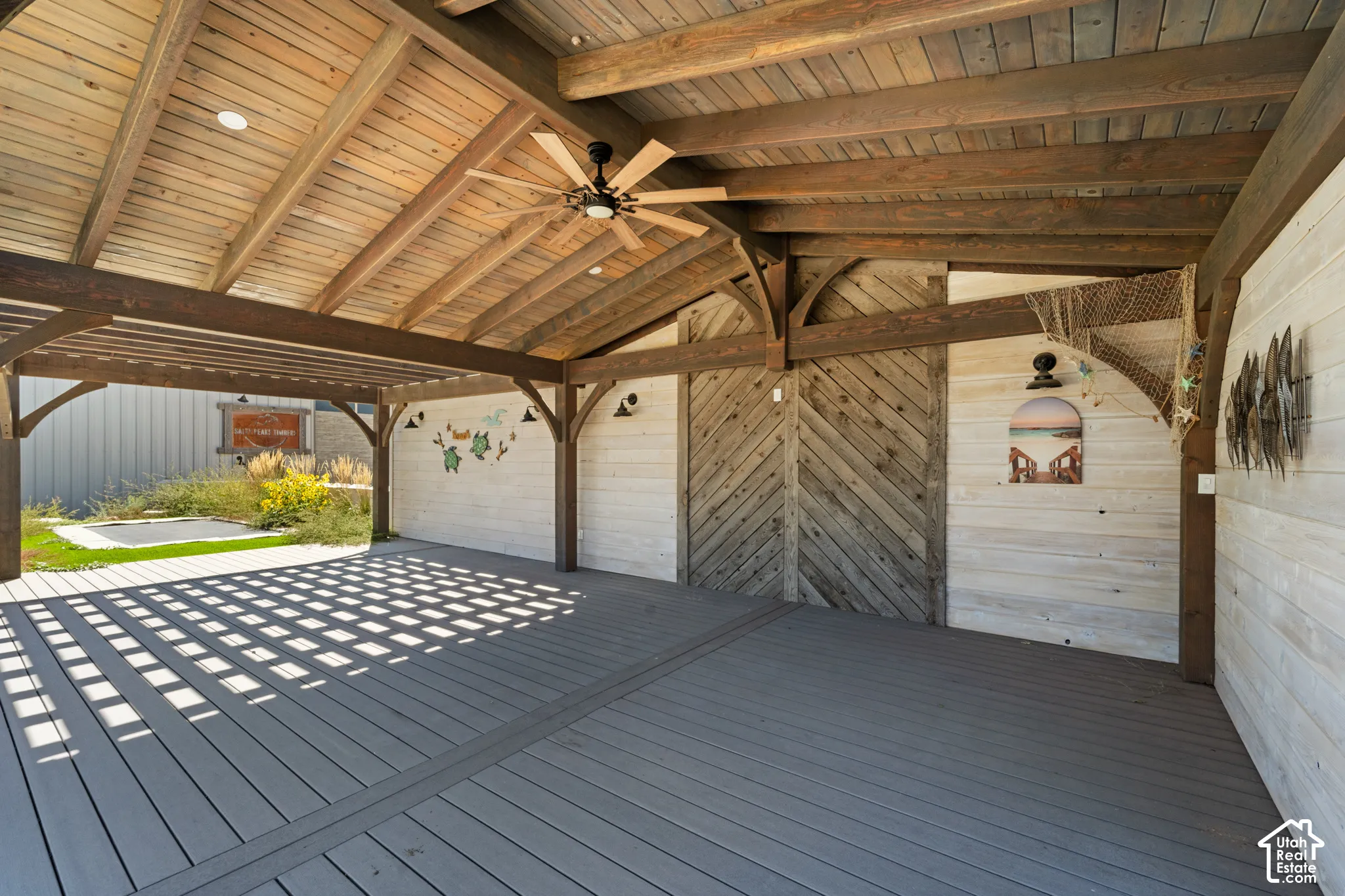 Expansive covered outdoor living area featuring a wood-finish ceiling, exposed wood beams, ceiling fan, and composite decking