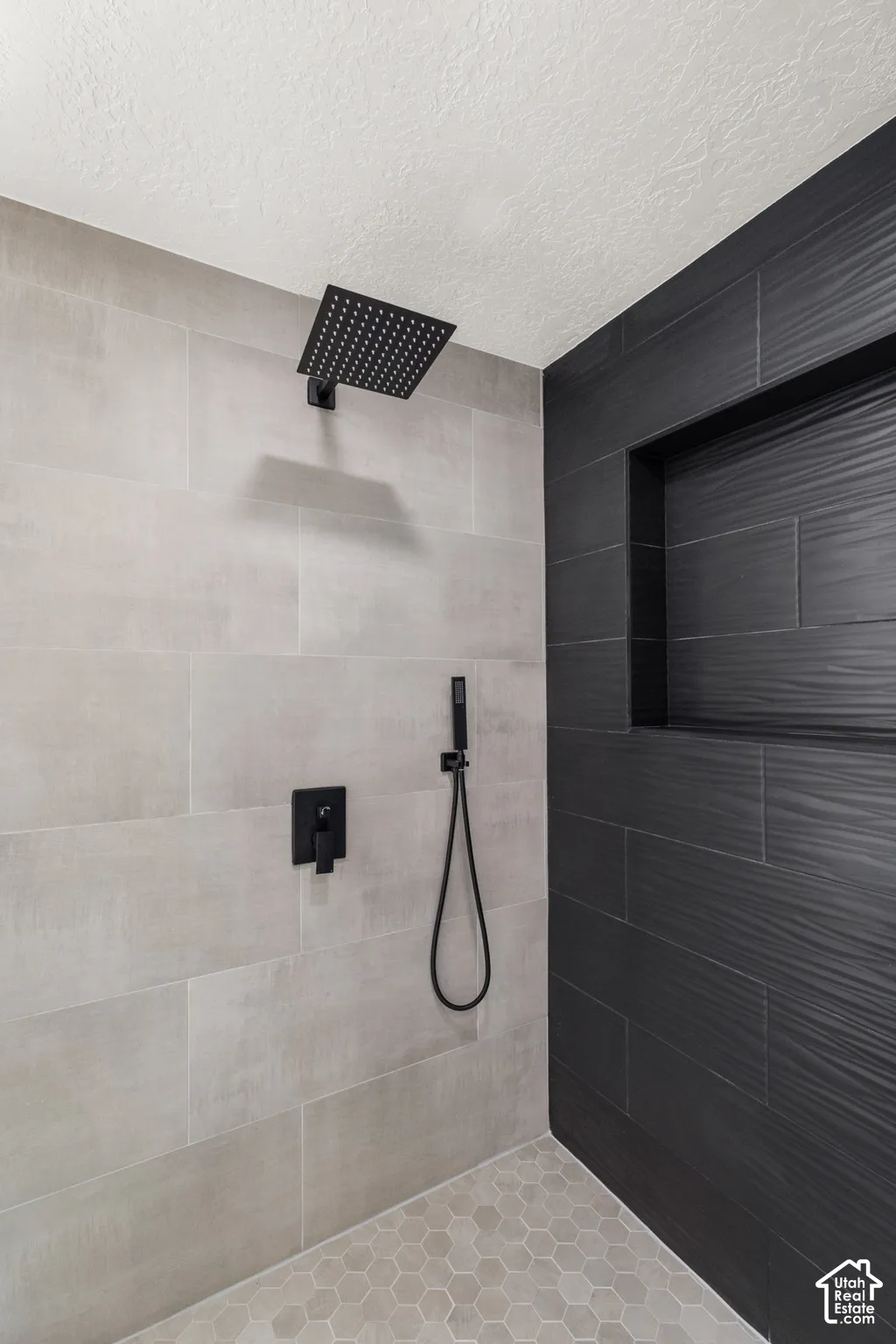 Walk-in shower featuring a matte black rain shower head, matte black handheld shower, and a matte black control panel