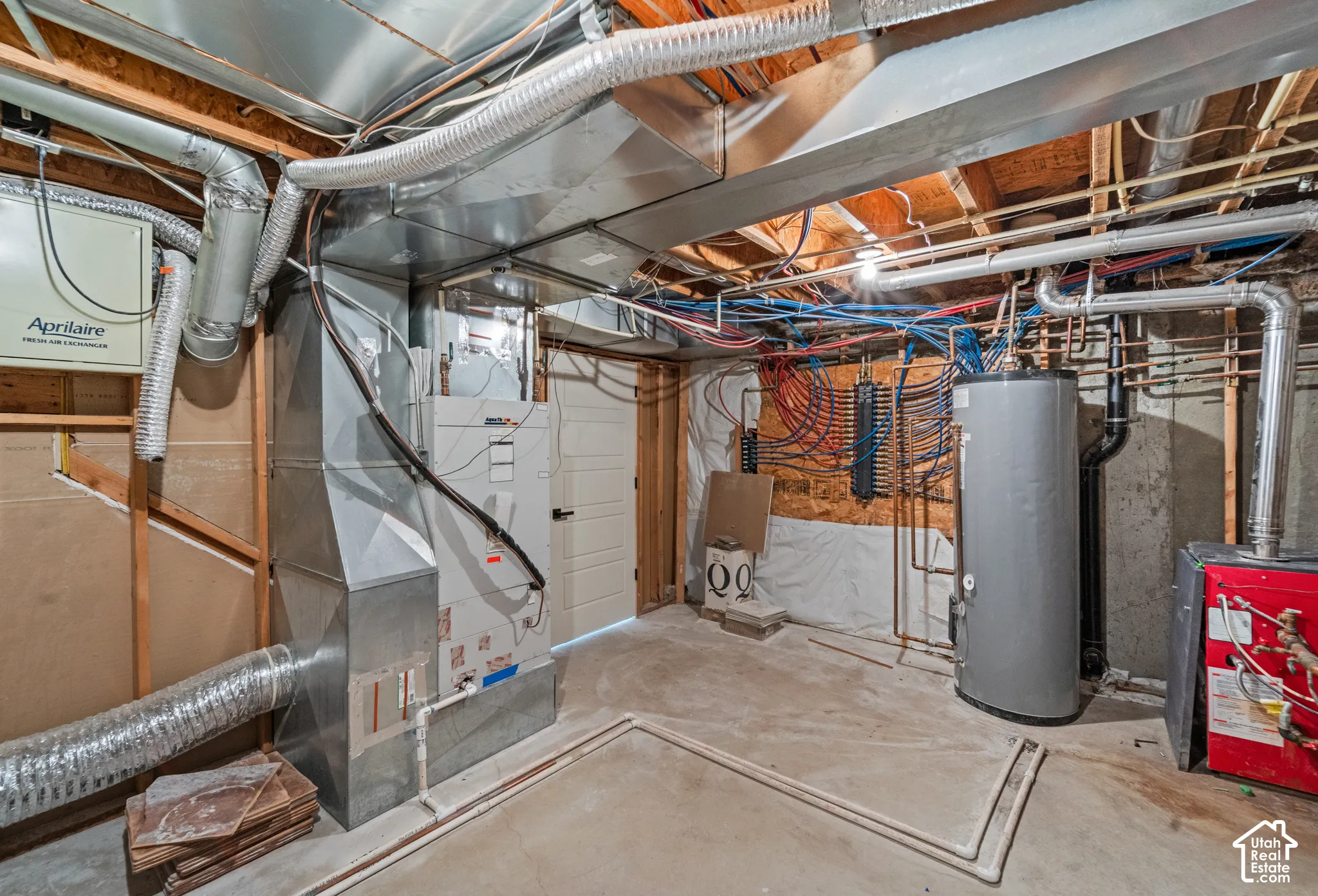 Concrete flooring with exposed ceiling joists, comprehensive ductwork, water heater, and mechanical systems