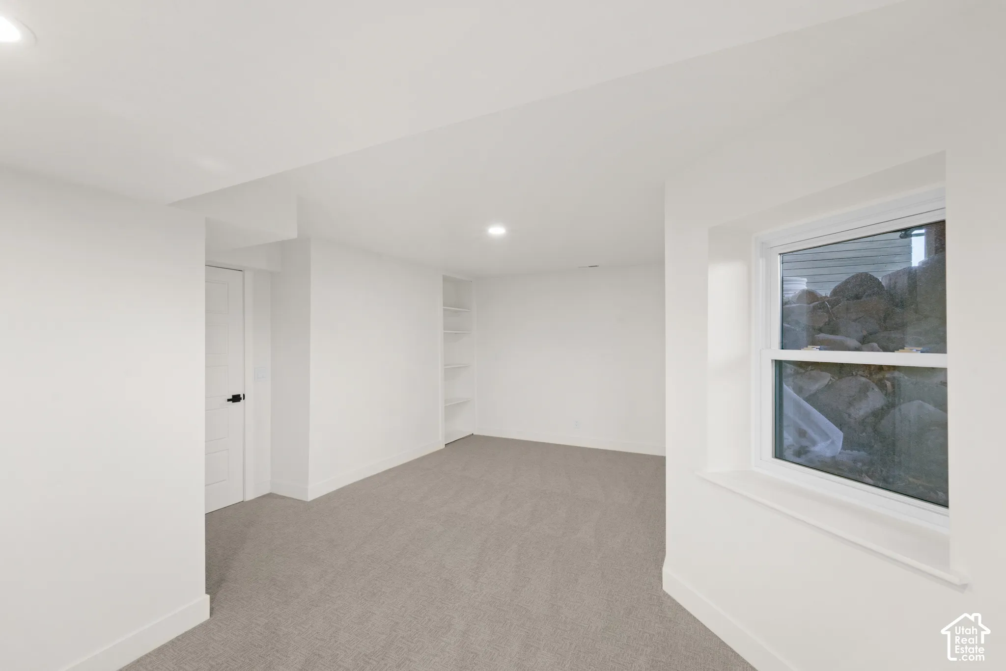 Recessed lighting, light gray carpet, and a built-in shelving unit