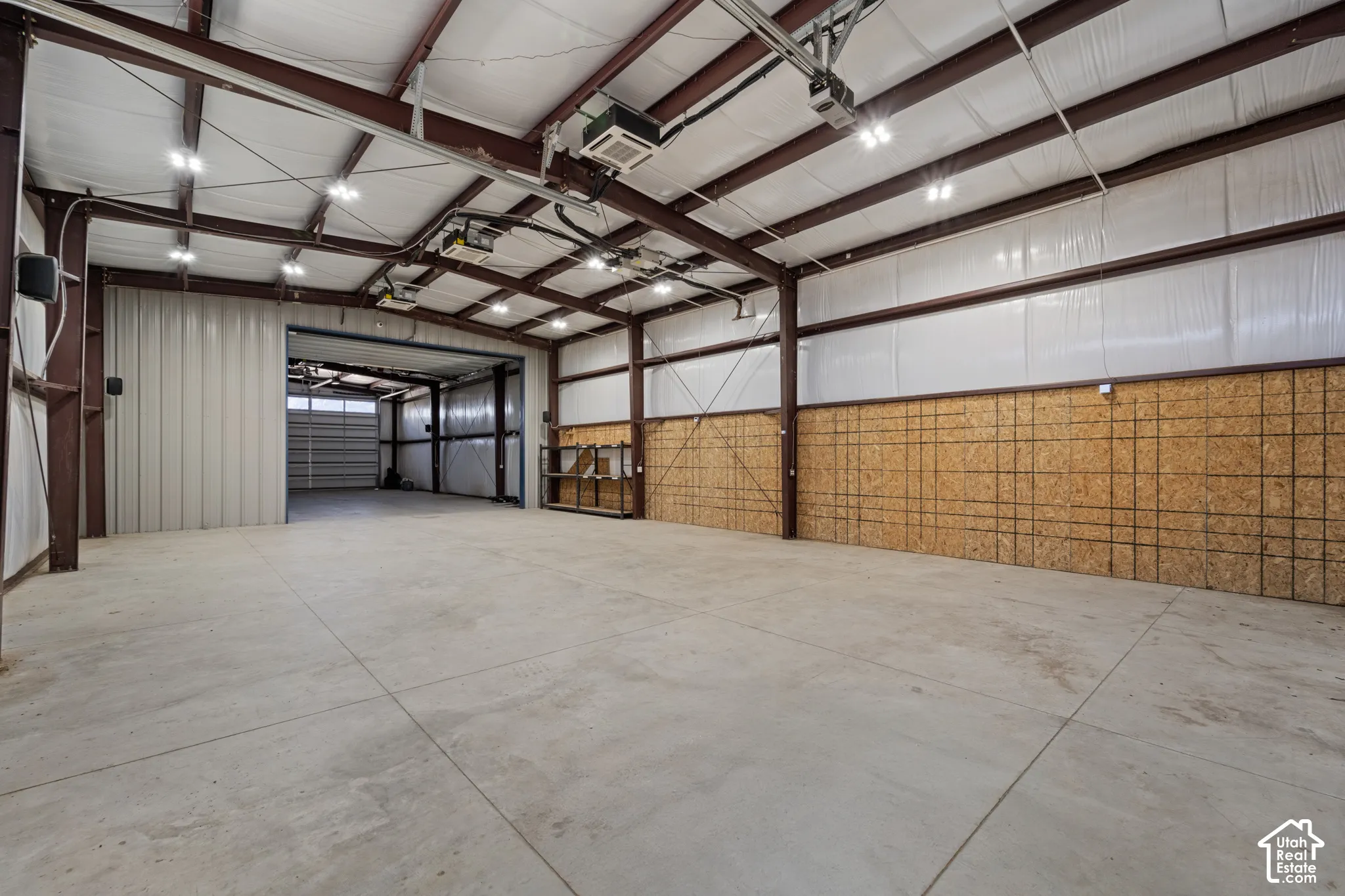 Spacious interior with exposed metal beams, concrete flooring, and high ceilings