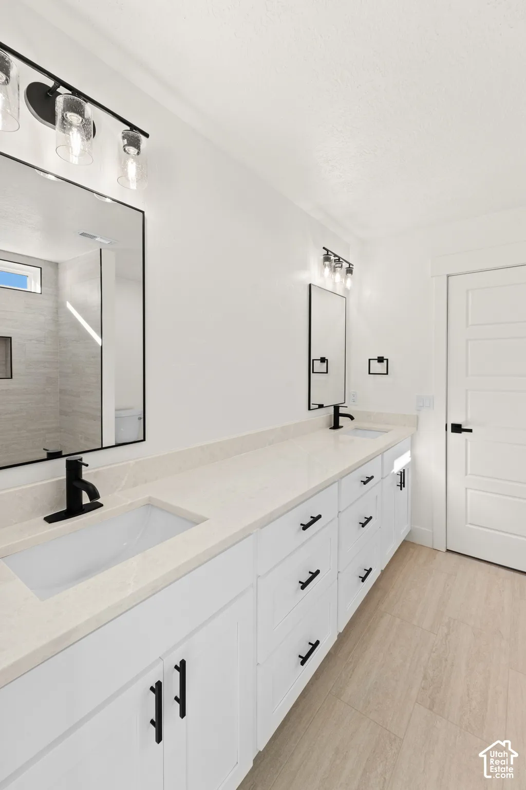 Dual vanity with white cabinetry, light-toned countertop, and black fixtures