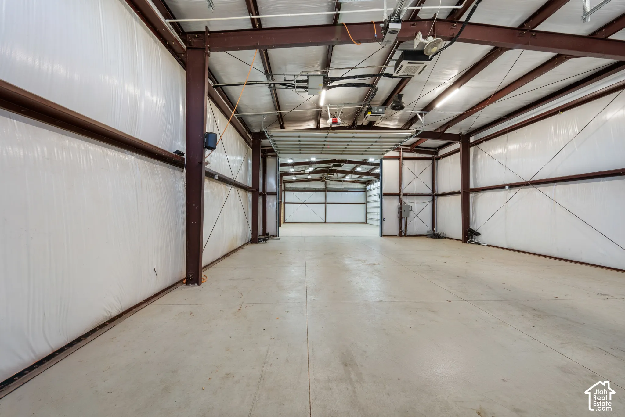 Expansive interior space featuring exposed steel beams, concrete flooring, and multiple garage doors