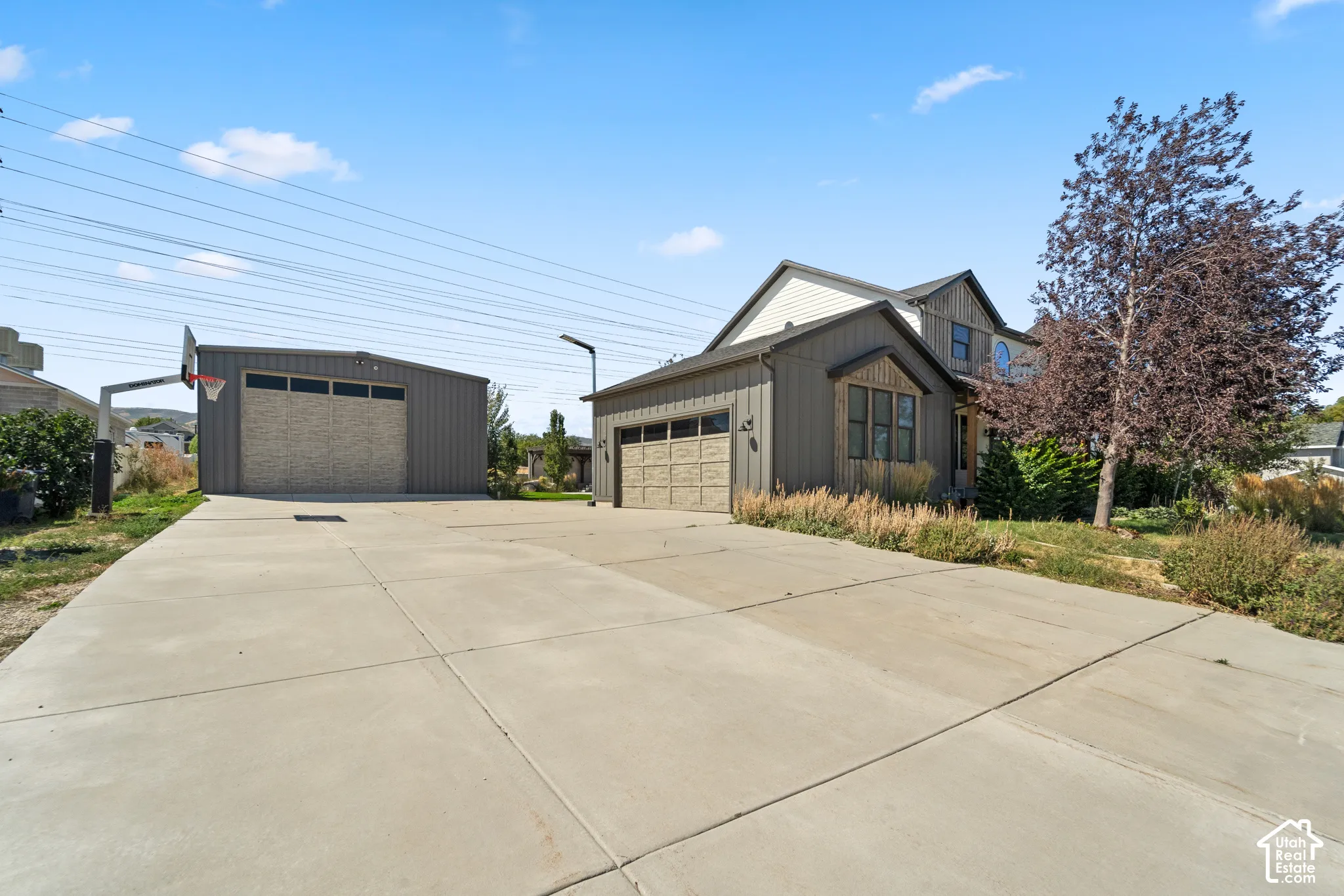 Expansive concrete driveway, detached garage with a brick-patterned door, and an additional attached garage