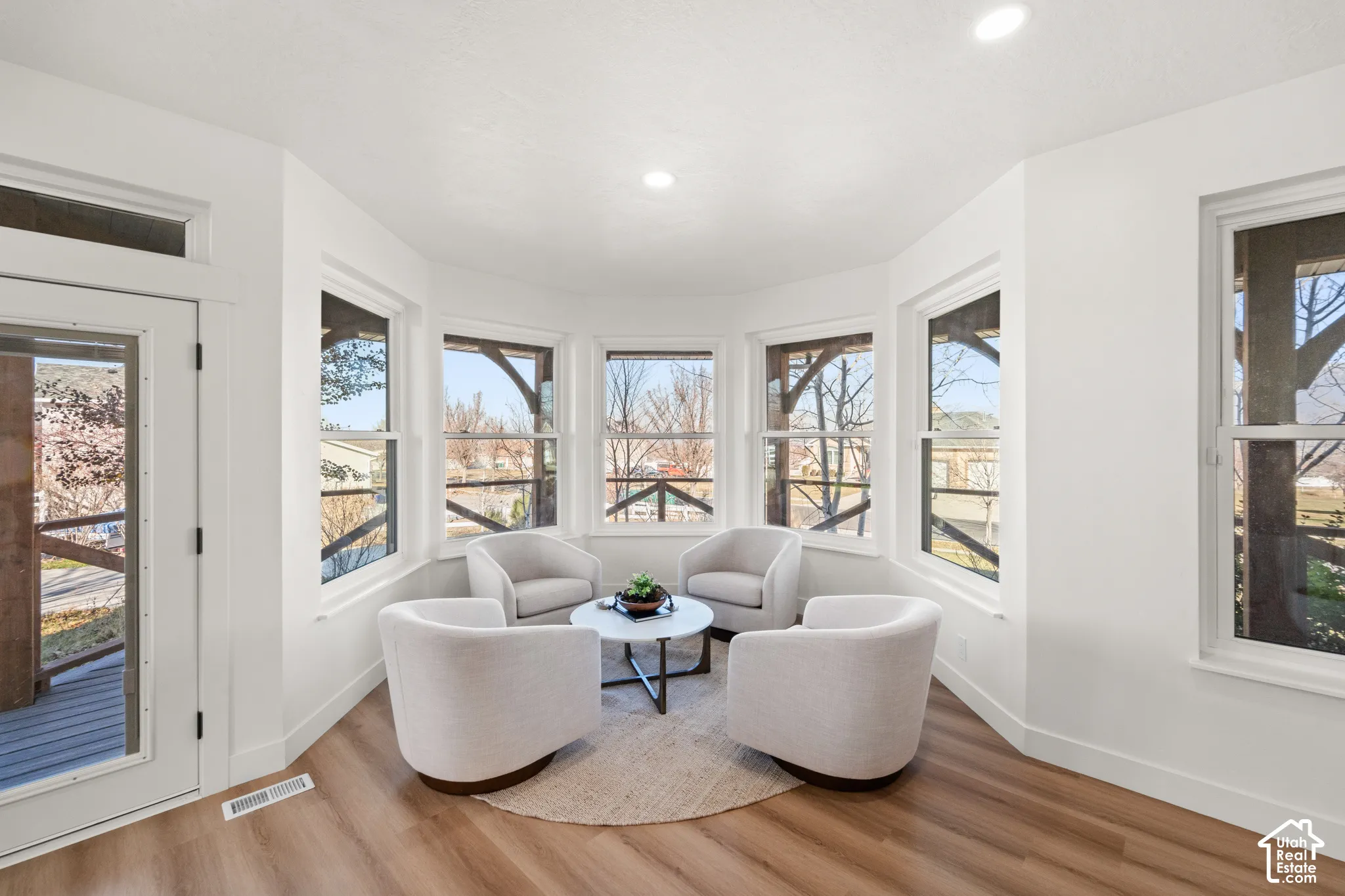 Bay window area with wood-finish flooring, recessed lighting, and a glass-paneled door