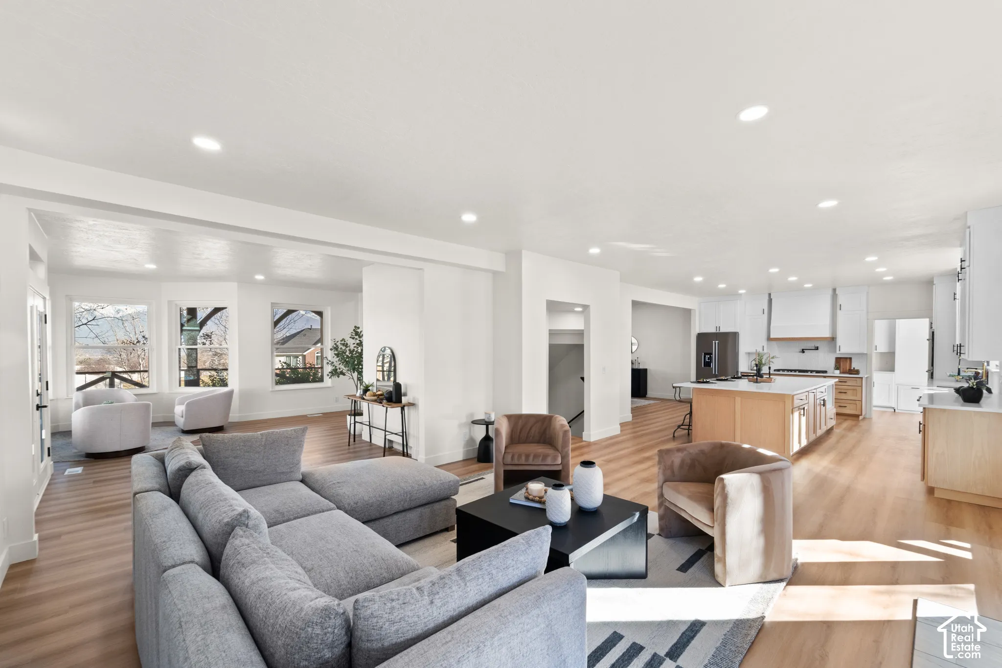 Spacious open-concept living area with wood-finish flooring, recessed lighting, and large windows