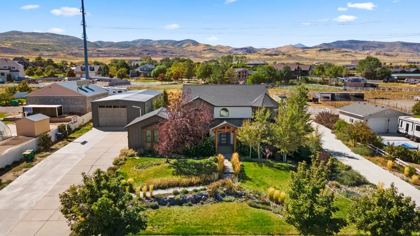 Property featuring a multi-level exterior, an attached garage, a detached accessory building, a paved driveway, and mature landscaping