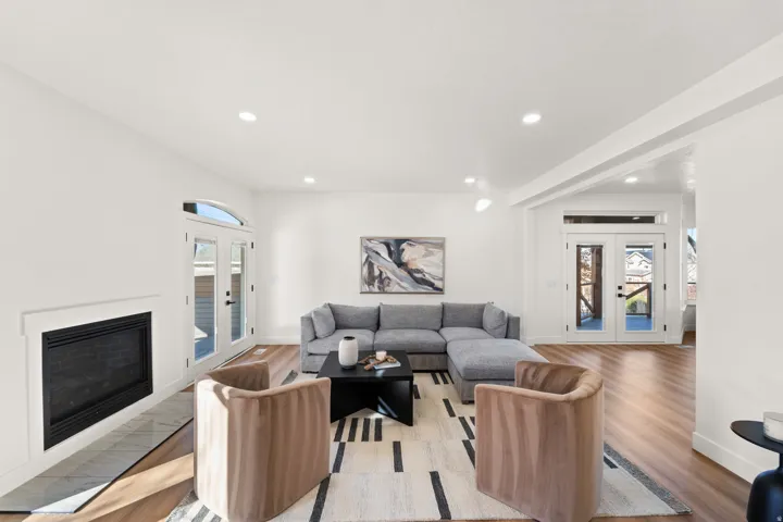 Open-concept living space with wood-finish flooring, a built-in fireplace featuring a tile hearth, recessed lighting, and white walls