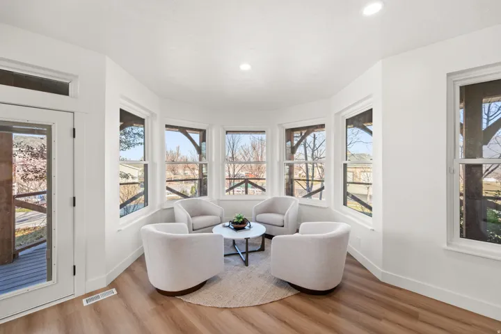 Bay window area with wood-finish flooring, recessed lighting, and a glass-paneled door