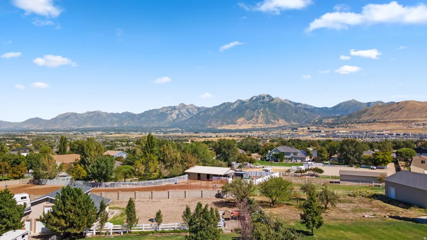 Expansive property featuring a flat, open lot, a white perimeter fence, and a distant mountain range backdrop