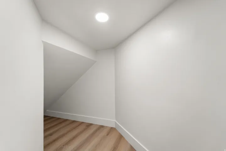 Recessed lighting, wood-finish flooring, white walls, angled ceiling, white trim