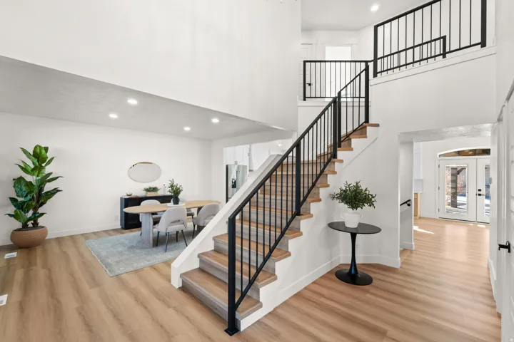 High ceilings, wood-finish flooring, recessed lighting, white walls, and black metal railings
