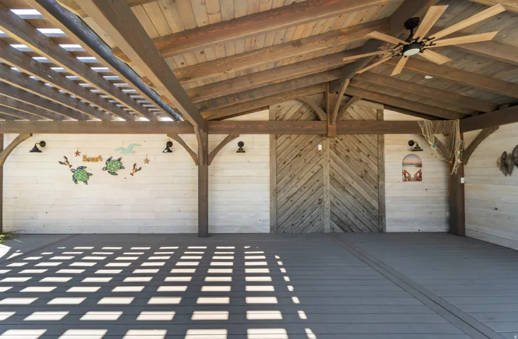 Expansive outdoor structure featuring a slatted pergola roof, a solid wood-beamed ceiling, and durable composite decking