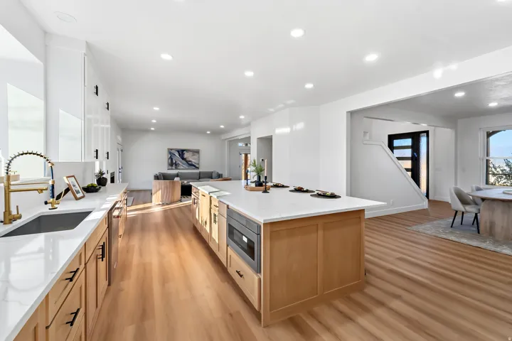 Bright kitchen featuring a large central island, light wood-finish flooring, white cabinetry, and recessed lighting