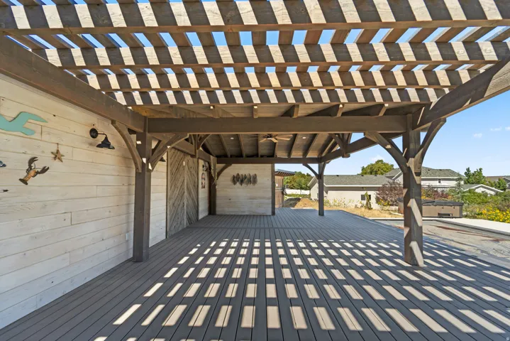 Expansive outdoor deck featuring a wooden pergola, composite decking, and a built-in ceiling fan
