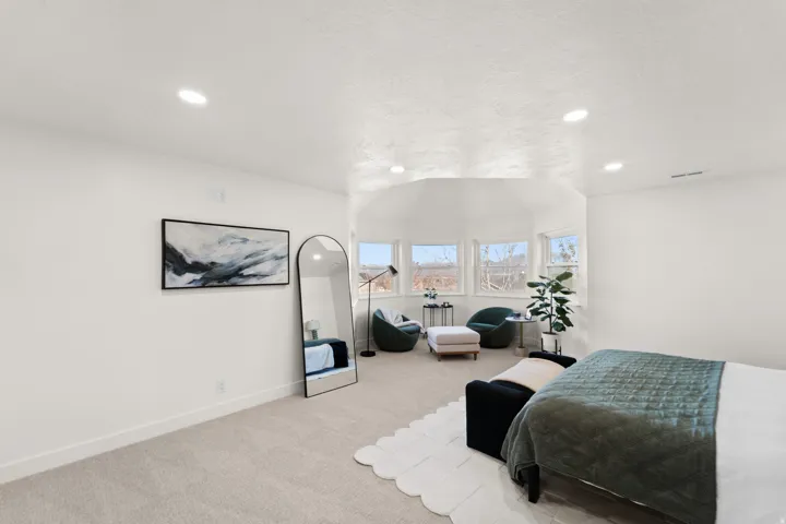 Recessed ceiling lighting, light-toned carpeting, white wall finishes, multiple windows, and a multi-faceted ceiling design