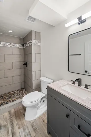 Walk-in shower with natural stone floor, subway tile walls, and mosaic accent