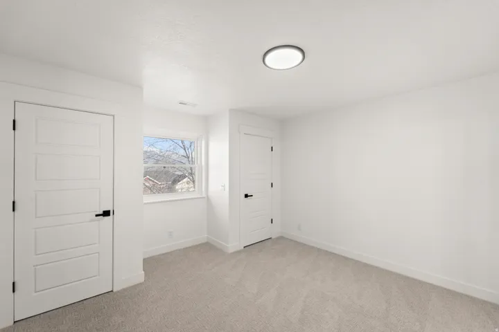 Light gray carpet flooring, white walls, and a contemporary ceiling light fixture