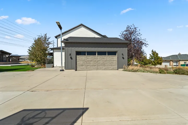 Attached garage with a wood-finish door and dark siding, complemented by white siding on the upper level