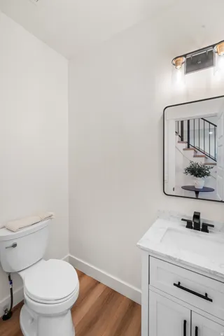 White vanity with a rectangular undermount sink, dark-toned faucet, and light-toned countertop