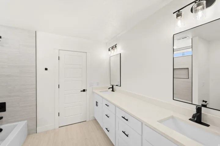 Dual vanity with matte black fixtures, light-toned countertops, and framed mirrors